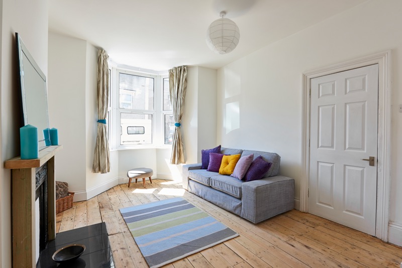 Modern renovated living room with grey sofa and colorful pillows - Property Flipping Success
